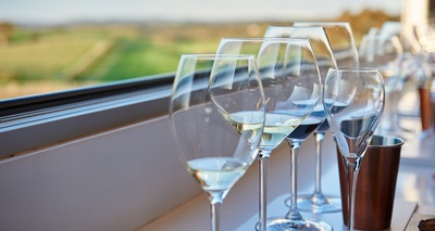 Wine glasses on an outdoor cellar door table, with a South Australian vineyard in the background
